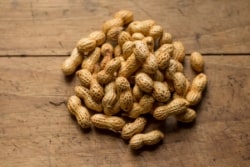 Photograph of peanuts on a wooden table.